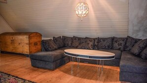 A cozy room with a sectional sofa, a small round table, a wooden chest, and a globe light.