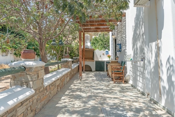 An outdoor patio with a pergola, stone walls, and a seating area with chairs and a table.