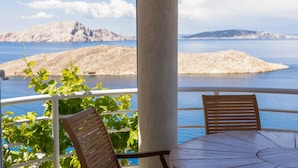 A balcony with a table and two chairs, overlooking a body of water and a mountainous landscape. - Nice apartment in Lukovo with house sea view (Lukovo)