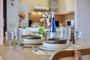A dining table with plates, bowls, glasses, and a bottle.