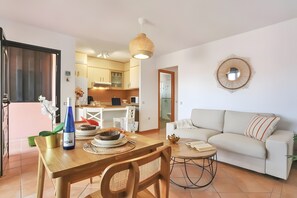 Un salon moderne comprenant un coin repas, un canapé, une table basse et une cuisine en arrière-plan.