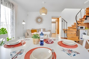 A dining area with a white table set for four, a bottle of Vina Tokoro wine, and a red placemat.