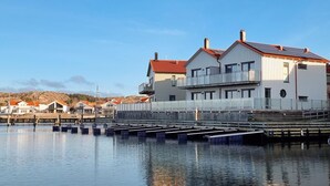 A waterfront building with a red roof, multiple balconies, and a dock extending into the water. - Beach front home in Rönnäng with sauna (Rönnäng)