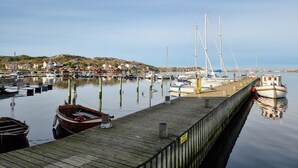 A wooden pier with boats docked, a clear sky, and houses in the background. - Beach front home in Rönnäng with sauna (Rönnäng)