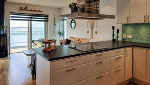 A modern kitchen with a large island, white cabinetry, and a view of the outdoors. - Beach front home in Rönnäng with sauna (Rönnäng)