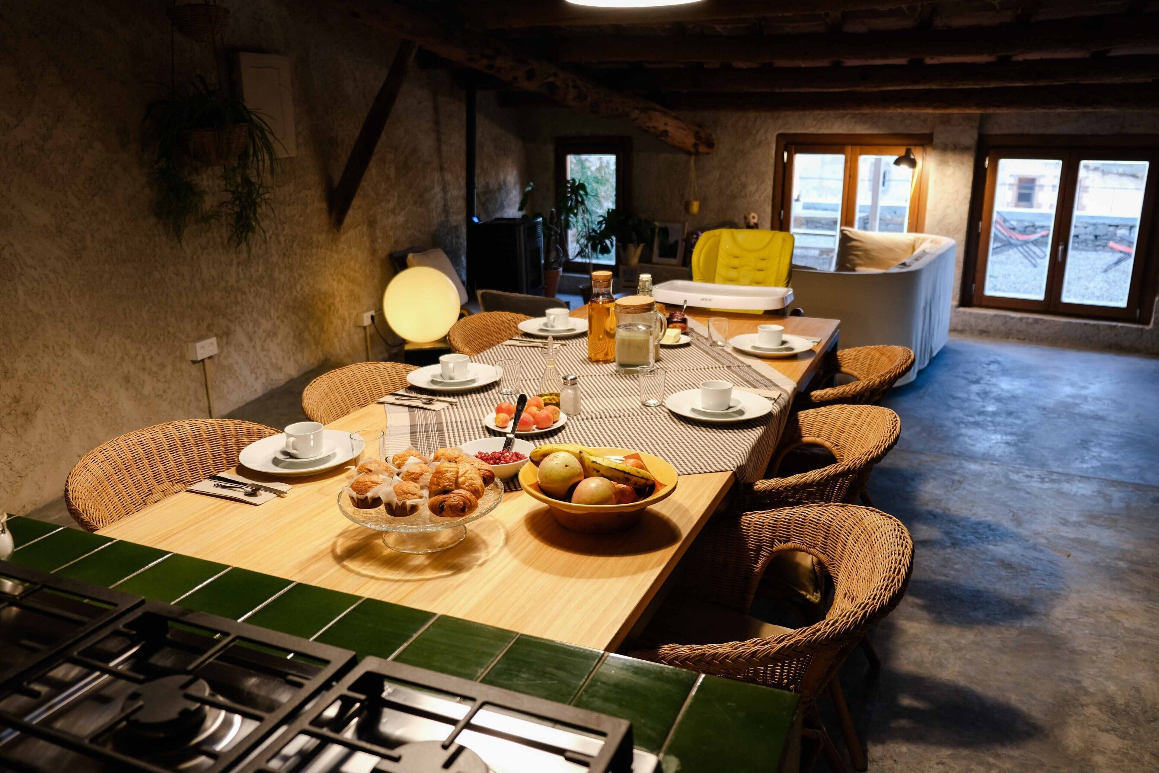 Zona pranzo con un tavolo lungo, sedie in vimini e vista sull'esterno.