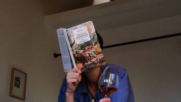 Una persona leyendo una revista y sosteniendo una copa de vino.