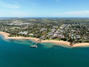 Ett flygbildsbild av ett bostadsområde vid kusten med en pir som sträcker sig ut i havet.