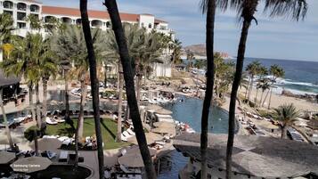 Un resort con zona de piscina, palmeras y vista al océano.