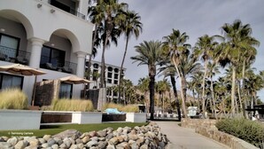 A hotel with a modern architectural design, featuring a multi-story structure with balconies, palm trees, and outdoor seating areas. - Ocean view beach suite (San José del Cabo)