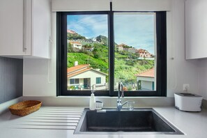 A kitchen with a large window, a sink, a toaster, and a basket. - Apartment 'Eden' with Mountain View, Balcony and Wi-Fi (Machico)