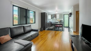 Un salon moderne avec un canapé en cuir, un téléviseur à écran plat et un coin repas comprenant une table et des chaises.