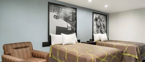 A hotel room with two beds, a chair, and two framed pictures on the wall.