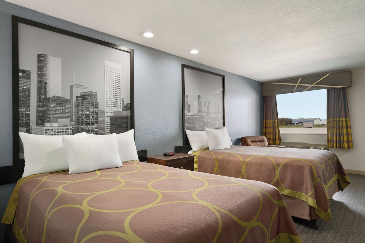 Habitación de hotel con dos camas, vistas a la ciudad y una ventana con cortinas.