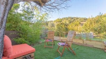 Eine Holzdielen-Terrasse mit zwei Holzstühlen und einer roten gepolsterten Bank.