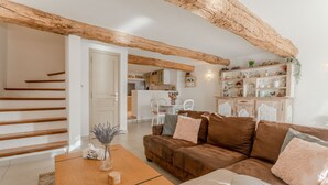 A living room with a brown leather sofa, a wooden coffee table, and a staircase. - Sainte-Maxime House: Private Terrace, Wi-Fi, and Air Conditioning (Le Plan)