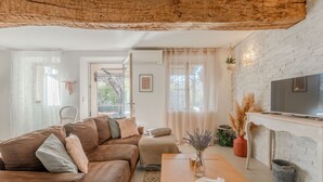 A living room with a brown leather sofa, a wooden coffee table, a TV, and a white brick wall. - Sainte-Maxime House: Private Terrace, Wi-Fi, and Air Conditioning (Le Plan)