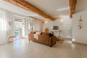 Un salon avec un canapé marron, un fauteuil blanc, un téléviseur et une cheminée.