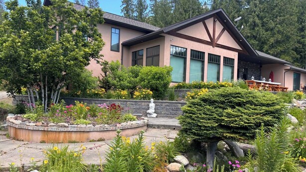 A modern house with a stone facade, large windows, and a well-maintained garden with various plants and flowers. - Mara Spring Lodges - Lodge 2 (Mara)