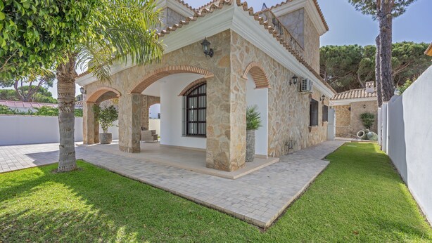Una casa de piedra con un patio, una entrada cubierta y un césped bien cuidado.