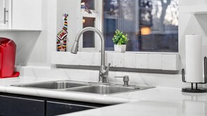 A kitchen with a double sink, a window with a view, and a small potted plant on the windowsill.