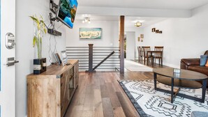 A modern living room with a wooden floor, a coffee table, a sofa, and a TV mounted on the wall.