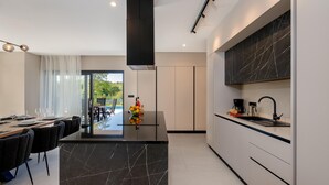 A modern kitchen with a central island, a dining area with a view, and a built-in stove. - Amazing home in Labin with private swimming pool, can be inside or outside (Labin)