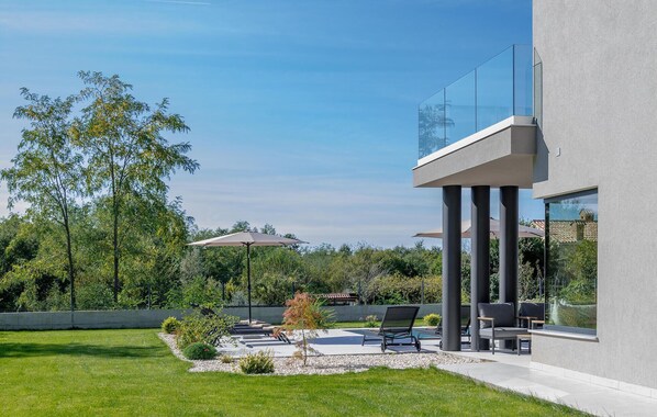 A modern outdoor patio with lounge chairs, a small tree, and a concrete pathway. - Amazing home in Labin with private swimming pool, can be inside or outside (Labin)