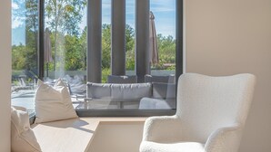 A modern room with a large window, a white armchair, and a sofa with cushions. - Amazing home in Labin with private swimming pool, can be inside or outside (Labin)