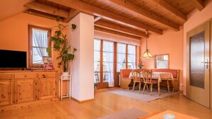 Un interior de madera con zona de comedor, televisor y planta.