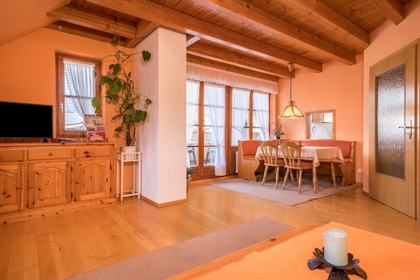 Un interior de madera con zona de comedor, televisor y planta.