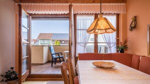 Un comedor con una mesa, sillas, una lámpara colgante y vistas a través de una puerta abierta.