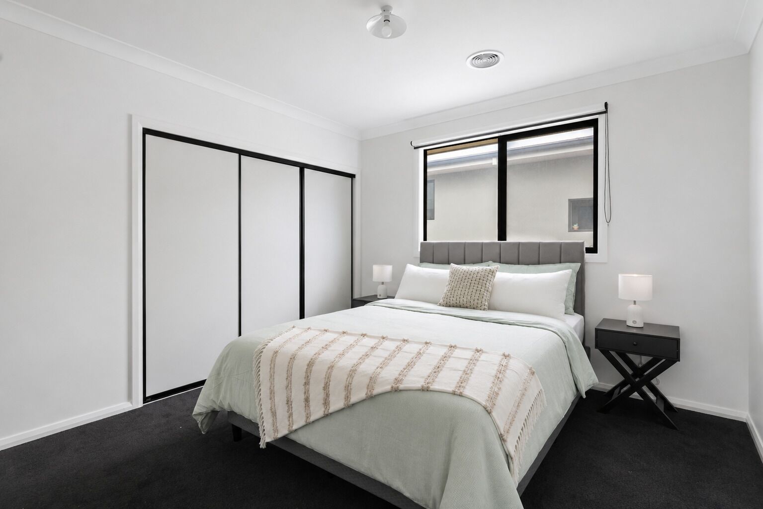 Une chambre à coucher moderne avec un lit, des tables de chevet, un miroir et une armoire.
