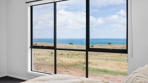 Una habitación con un ventanal grande que ofrece vista al mar y al paisaje con césped.