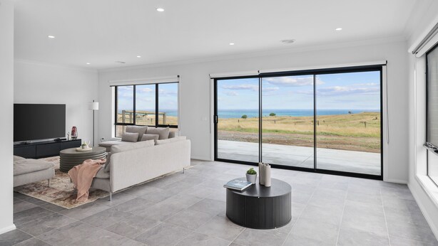 Una sala de estar moderna con un amplio ventanal corredero que ofrece una vista panorámica al exterior.