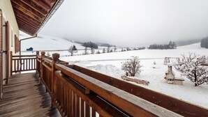 A wooden balcony with a view of a snowy landscape and distant hills. - Apartment 'Winter' with Mountain View, Shared Garden and Wi-Fi (Valle di Casies)