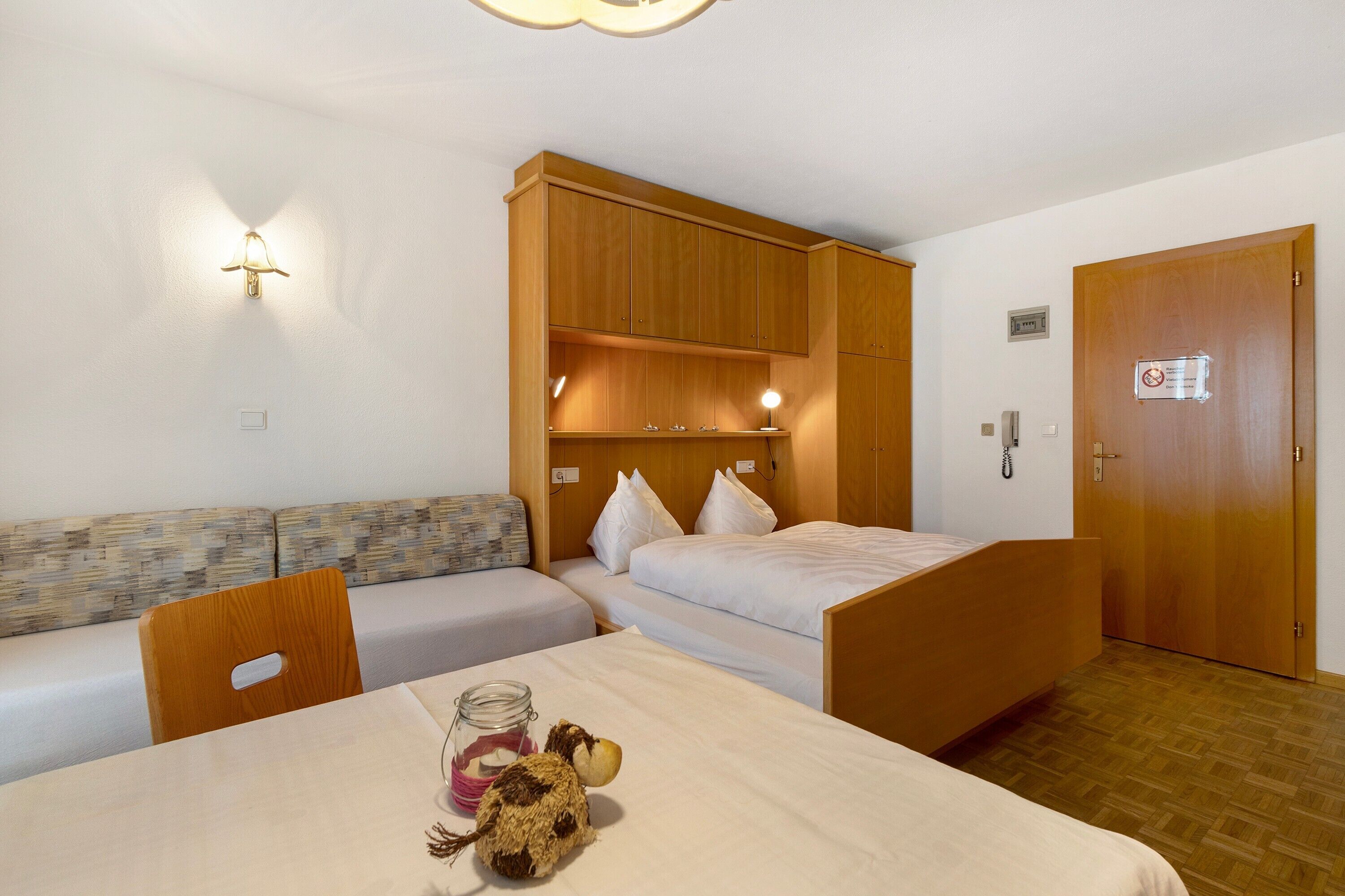 Une chambre d’hôtel comprenant un lit, un canapé, une table avec une lampe et un luminaire fixé au mur.