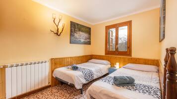 Een slaapkamer met twee bedden, een radiator, een schilderij en een raam.