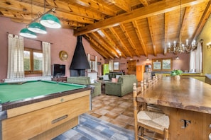 Un interior de madera con mesa de billar, sofás y una larga mesa de comedor.