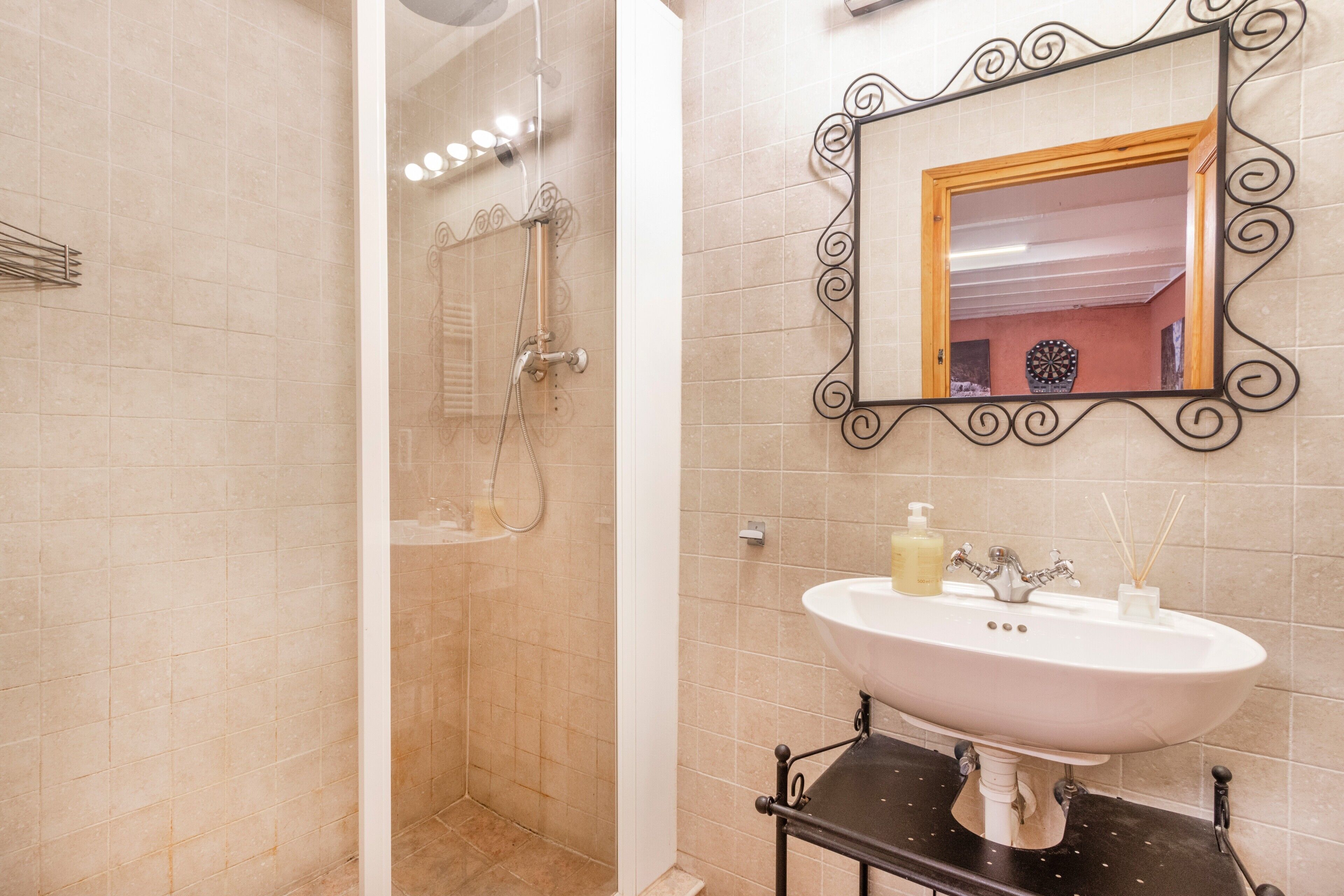 Een badkamer met een douche, een wastafel met spiegel en een handdoekrek.