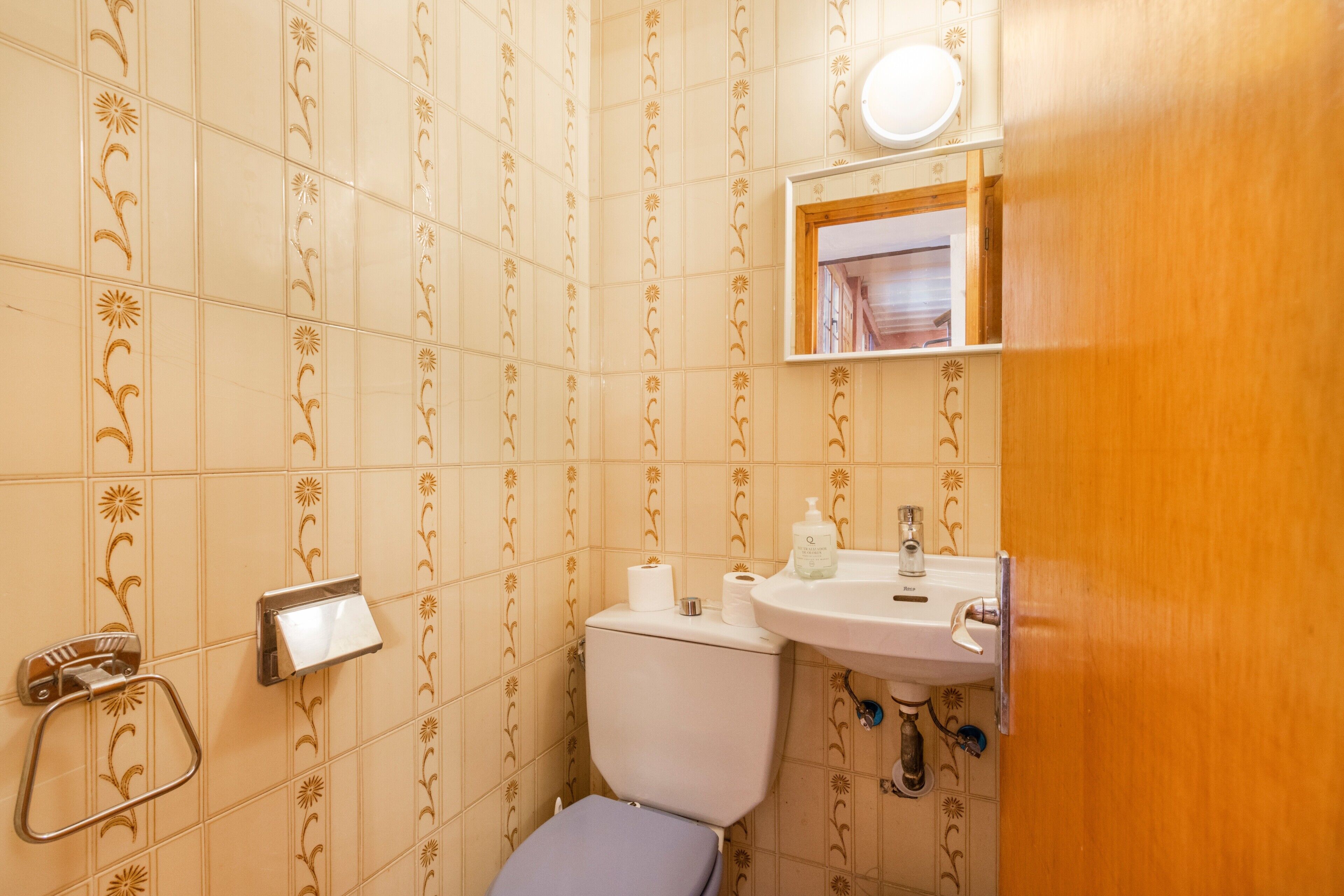 Un baño con inodoro, lavamanos y perchero para toallas.
