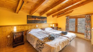 A bedroom with a wooden ceiling, a bed with a leopard print bedspread, a nightstand, and a window with curtains. - Country House 'Sisquet' with Mountain View, Private Terrace and Wi-Fi (Montcortès)