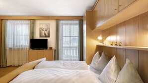 Una habitación de hotel con cama, televisor, escritorio y ventana con cortinas.