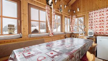 Ein gemütliches Holzhaus mit großen Fenstern, einem Tisch mit herzförmigem Tischläufer und einem Kühlschrank.