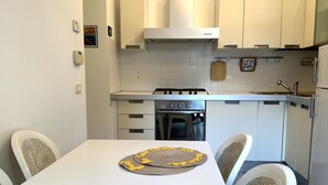 Een keuken met witte kastjes, een fornuis en een spoelbak.
