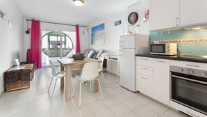 A modern kitchen with white cabinets, a dining table with chairs, a refrigerator, a microwave, and an oven.