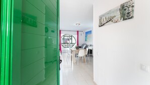 A room with a green door, a dining area with chairs and a table, and a wall with a Buddha painting.