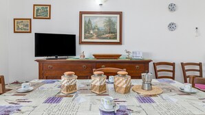 Un coin repas avec une table mise pour le thé, un téléviseur et des œuvres d’art encadrées accrochées au mur.