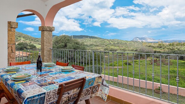 Un balcon avec une table dressée pour le dîner, offrant une vue sur un paysage montagneux.