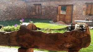 Ein rustikales Steinhaus mit Holztür, Steinmauer und Garten mit Blumen und Gras.